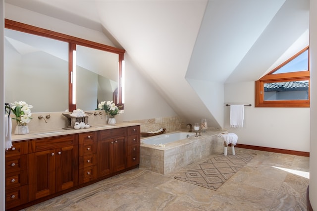 bathroom featuring tile patterned flooring, lofted ceiling, tiled tub, and vanity