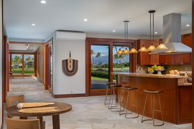 kitchen featuring an AC wall unit, kitchen peninsula, island exhaust hood, decorative backsplash, and pendant lighting