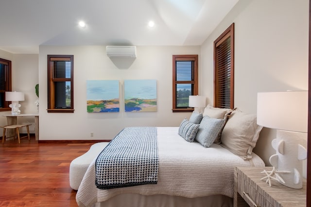 bedroom featuring a wall mounted air conditioner and hardwood / wood-style flooring