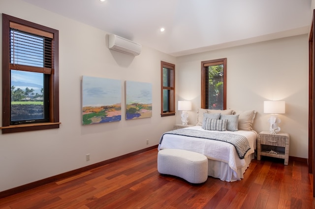 bedroom with a wall unit AC and dark hardwood / wood-style floors