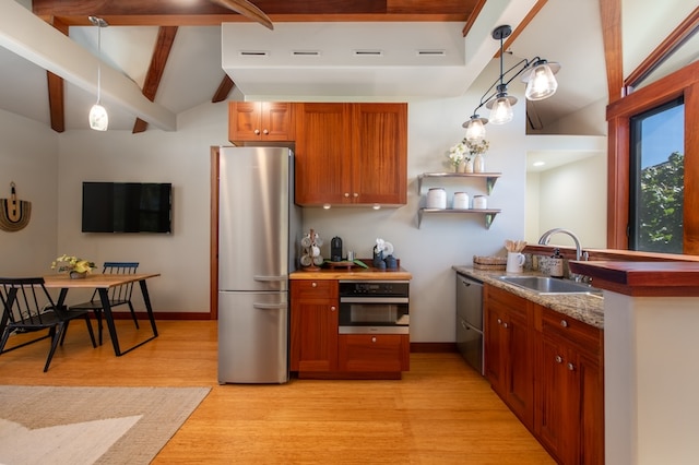 kitchen with vaulted ceiling with beams, light hardwood / wood-style floors, appliances with stainless steel finishes, pendant lighting, and sink