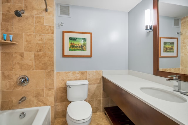 full bathroom with tiled shower / bath, toilet, vanity, tile walls, and tile patterned floors