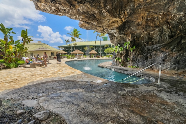 view of swimming pool with pool water feature and a patio area