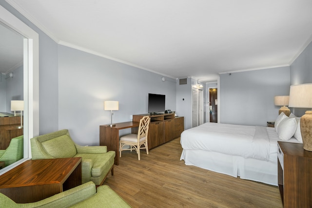 bedroom with ensuite bath, crown molding, and wood-type flooring