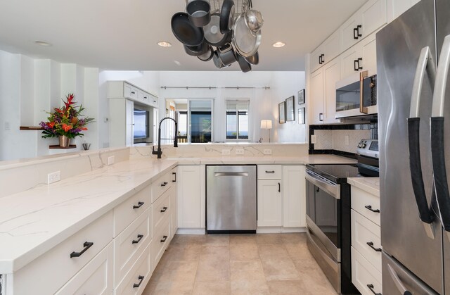 kitchen featuring stainless steel appliances, light tile patterned floors, white cabinets, light stone countertops, and kitchen peninsula