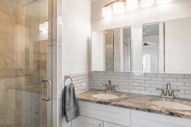 bathroom featuring double sink vanity, backsplash, and walk in shower