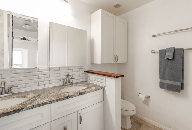 bathroom with toilet, tile patterned flooring, double sink vanity, and decorative backsplash