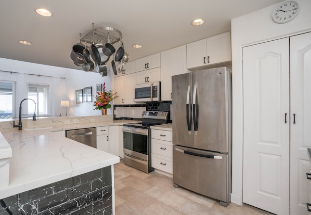 kitchen featuring appliances with stainless steel finishes, backsplash, white cabinetry, light stone counters, and light tile patterned floors