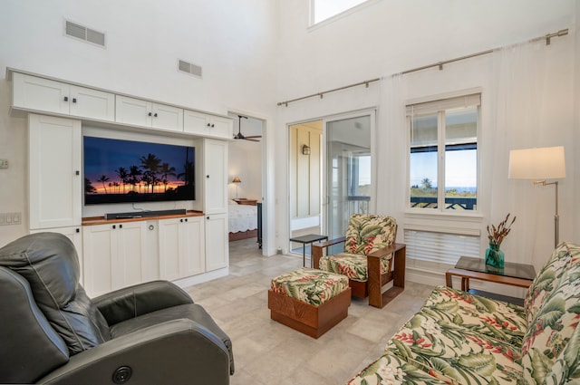 living room featuring ceiling fan, light tile patterned flooring, and a towering ceiling