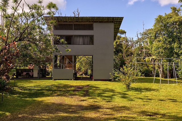 rear view of property featuring a lawn and stucco siding