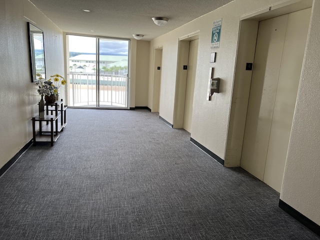 101 Hilo Lagoon Ctr Unit 401, Hilo, HI 96720 - hall with dark colored carpet, a wall of windows, a textured wall, and elevator