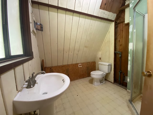 bathroom with vaulted ceiling, tile patterned floors, toilet, and wooden walls