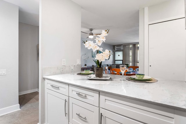 kitchen with ceiling fan, white cabinetry, light tile patterned flooring, and light stone countertops