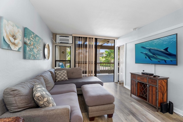 living room with expansive windows, light hardwood / wood-style flooring, and a wall mounted AC