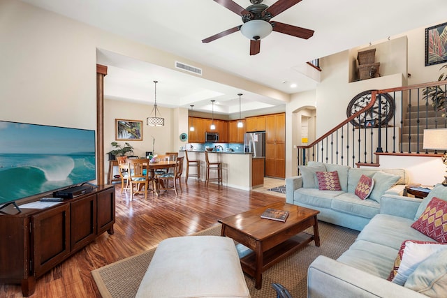 living room with hardwood / wood-style floors, ceiling fan, and a tray ceiling