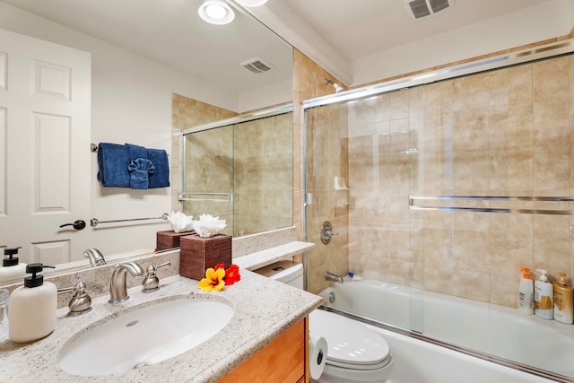 full bathroom featuring combined bath / shower with glass door, vanity, and toilet