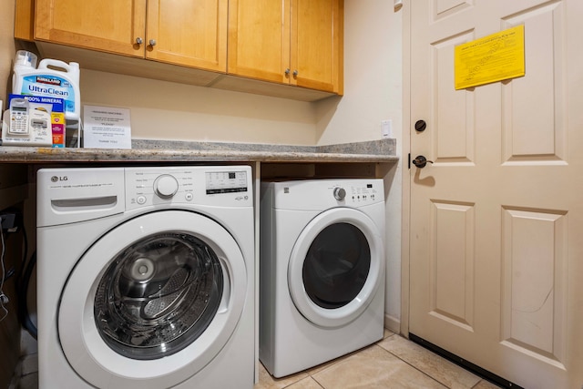 washroom featuring washer and clothes dryer, cabinets, and light tile patterned floors