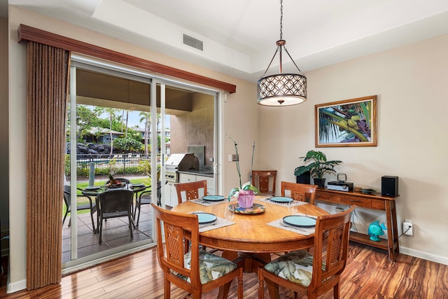 dining area with a raised ceiling and wood-type flooring