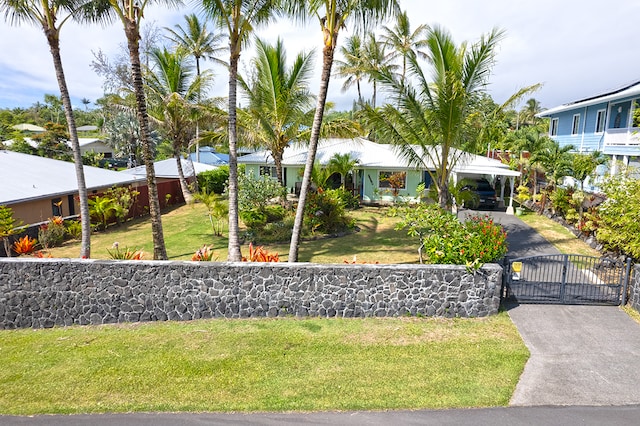 exterior space with aphalt driveway, an attached carport, a front yard, and a gate