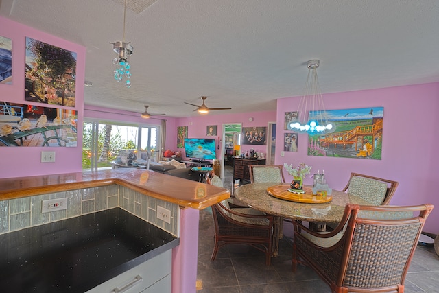 kitchen featuring a textured ceiling, hanging light fixtures, ceiling fan with notable chandelier, and tile patterned floors