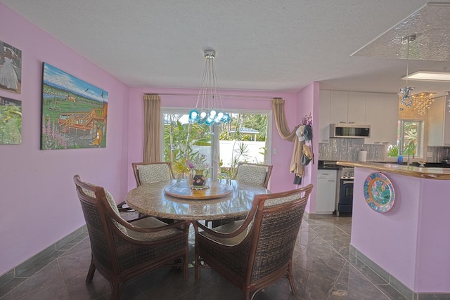 dining room featuring a chandelier, a textured ceiling, and baseboards