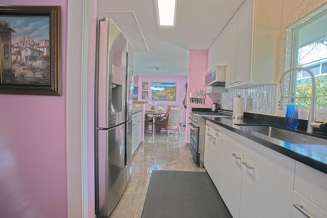 kitchen featuring appliances with stainless steel finishes, white cabinetry, a sink, and backsplash