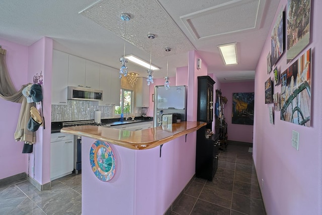 kitchen featuring stainless steel appliances, white cabinetry, decorative backsplash, a kitchen bar, and pendant lighting