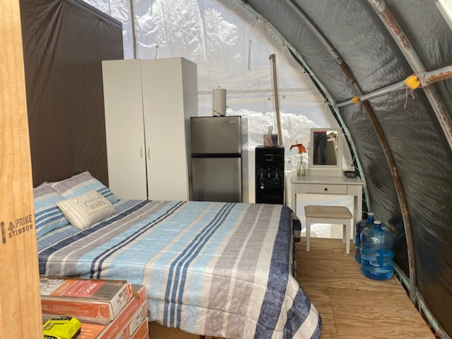 bedroom with wood-type flooring and stainless steel fridge