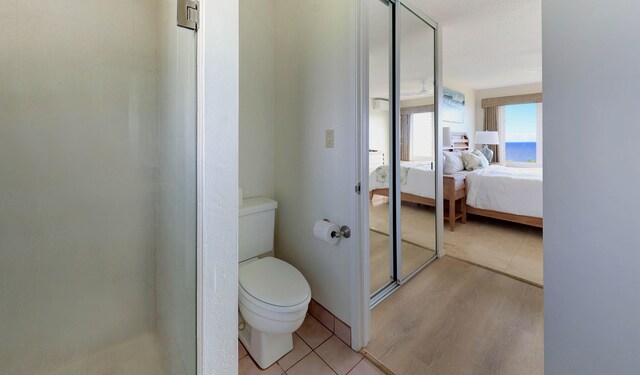 bathroom featuring hardwood / wood-style flooring, a shower, and toilet