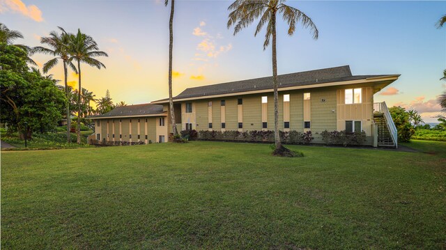 back house at dusk featuring a lawn