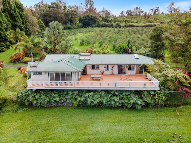 rear view of property featuring a lawn, a deck, and fence