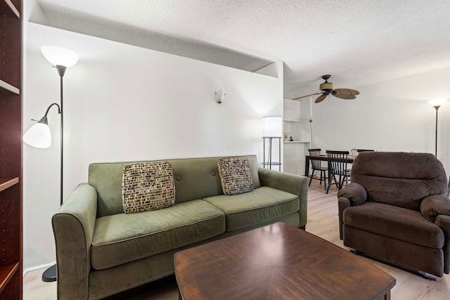 living room featuring a textured ceiling, light hardwood / wood-style flooring, and ceiling fan