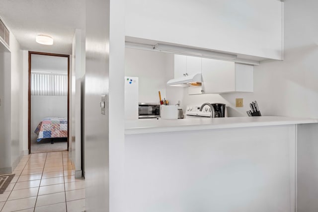 kitchen featuring a textured ceiling, light tile patterned flooring, white cabinetry, and stove