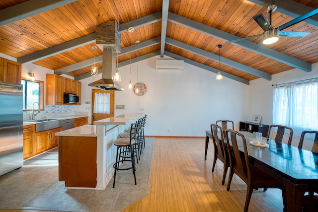 kitchen featuring island range hood, hanging light fixtures, sink, a kitchen island, and appliances with stainless steel finishes