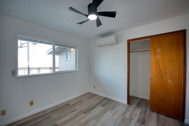 unfurnished bedroom featuring a closet, a wall mounted air conditioner, ceiling fan, and light hardwood / wood-style flooring