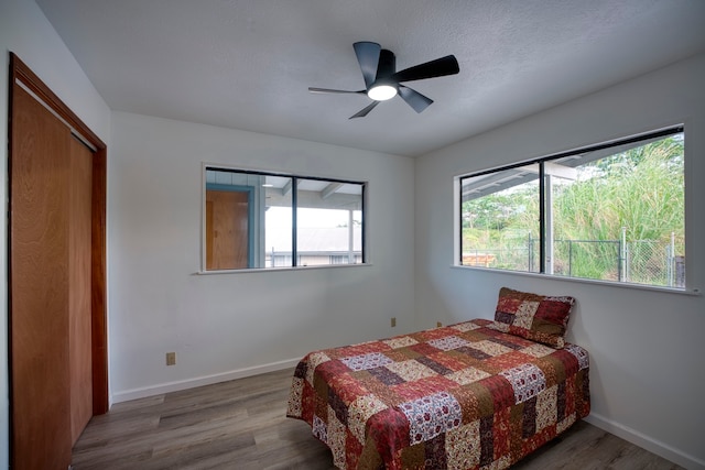 bedroom featuring a closet, wood-type flooring, ceiling fan, and a textured ceiling