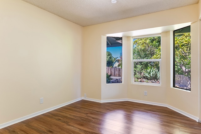 empty room with a textured ceiling and dark wood-type flooring