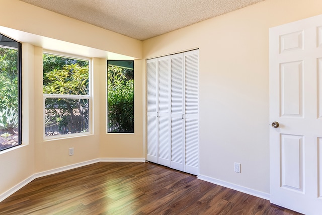 unfurnished bedroom featuring a textured ceiling and dark wood-type flooring