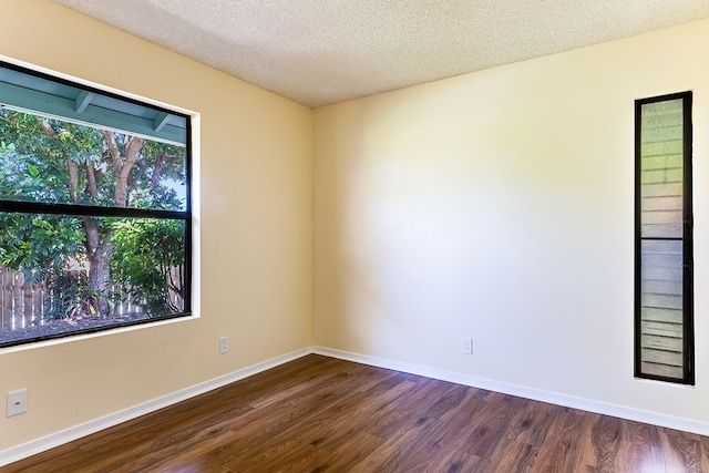 unfurnished room with a textured ceiling and dark wood-type flooring