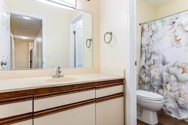 bathroom with a textured ceiling, hardwood / wood-style floors, vanity, and toilet