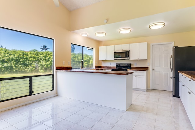 kitchen with light tile patterned floors, white cabinets, appliances with stainless steel finishes, and kitchen peninsula