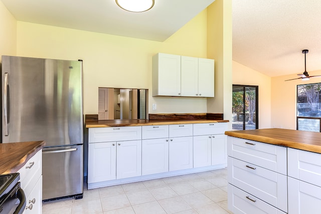 kitchen featuring lofted ceiling, white cabinetry, wood counters, and stainless steel fridge