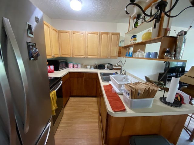 kitchen featuring light hardwood / wood-style floors, a textured ceiling, sink, a kitchen breakfast bar, and appliances with stainless steel finishes