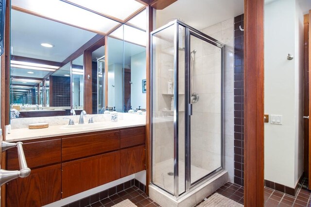 bathroom featuring a shower with shower door, vanity, and tile patterned floors