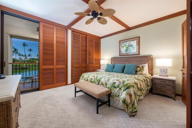 bedroom with light carpet, two closets, a water view, and ceiling fan