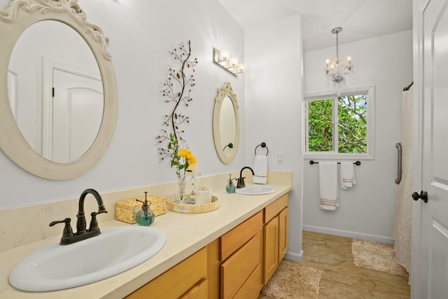 full bathroom with baseboards, double vanity, a sink, and a notable chandelier