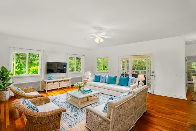 living room featuring radiator heating unit, wood finished floors, a ceiling fan, and baseboards