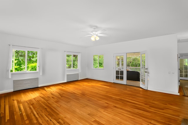 unfurnished living room featuring radiator, baseboards, ceiling fan, and light wood finished floors