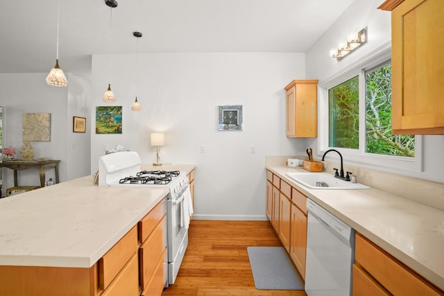 kitchen with white appliances, a sink, baseboards, hanging light fixtures, and light wood-type flooring