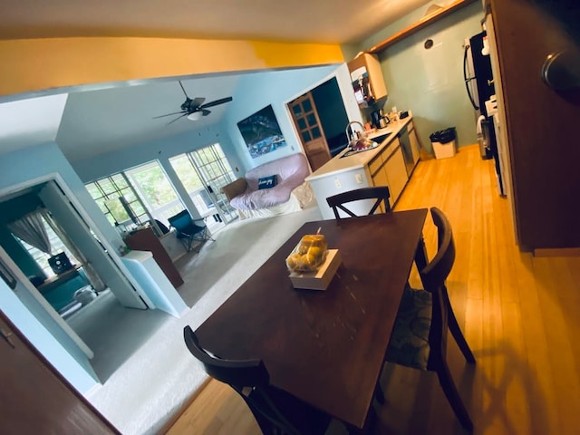 living room with ceiling fan, vaulted ceiling, sink, and light wood-type flooring